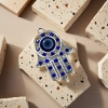 A fashionable and individual necklace with a silver hand-shaped pendant set with blue gemstones and blue eye ornaments Specification image